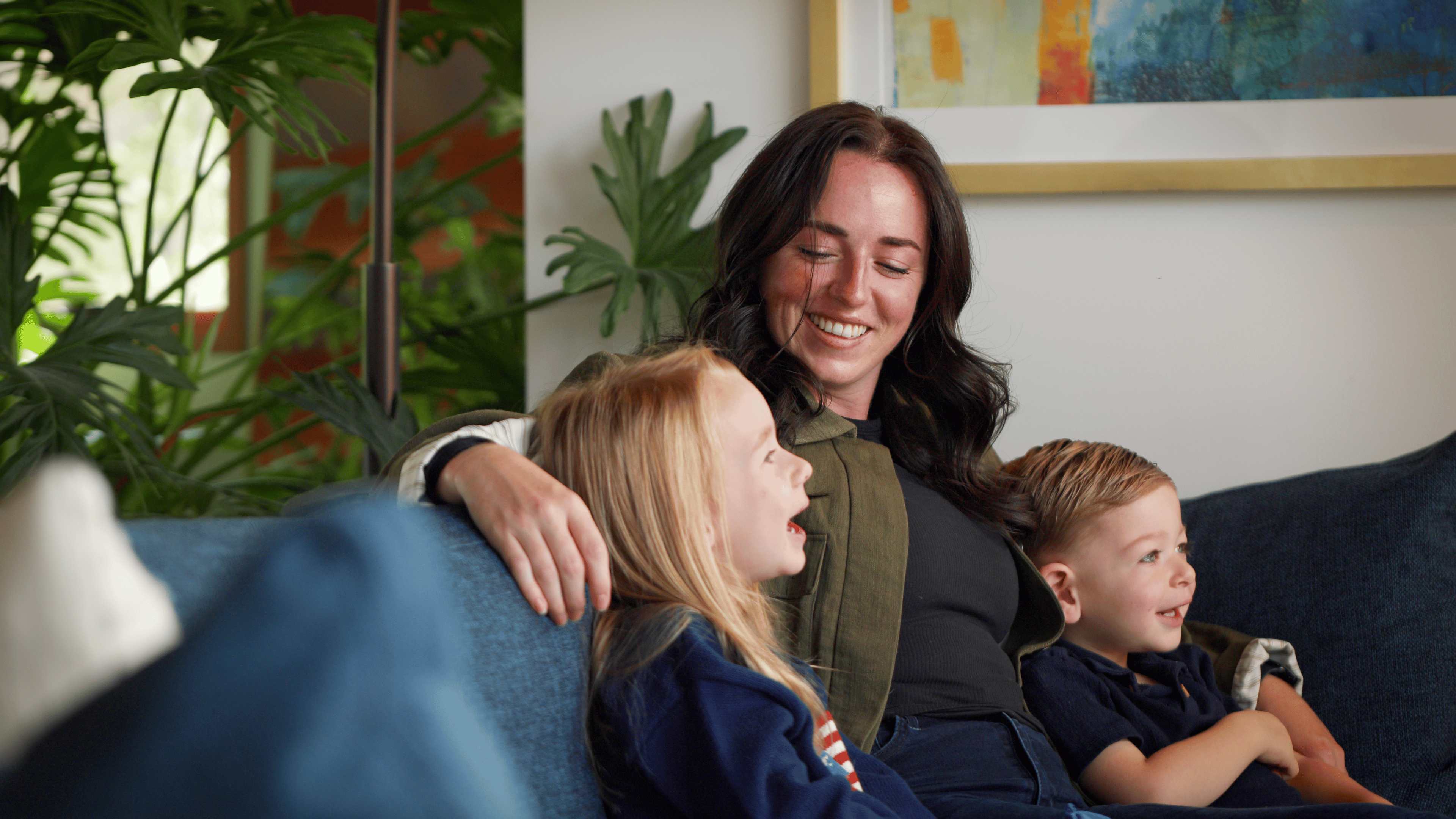 A mother and her two children relaxing together on a sofa.