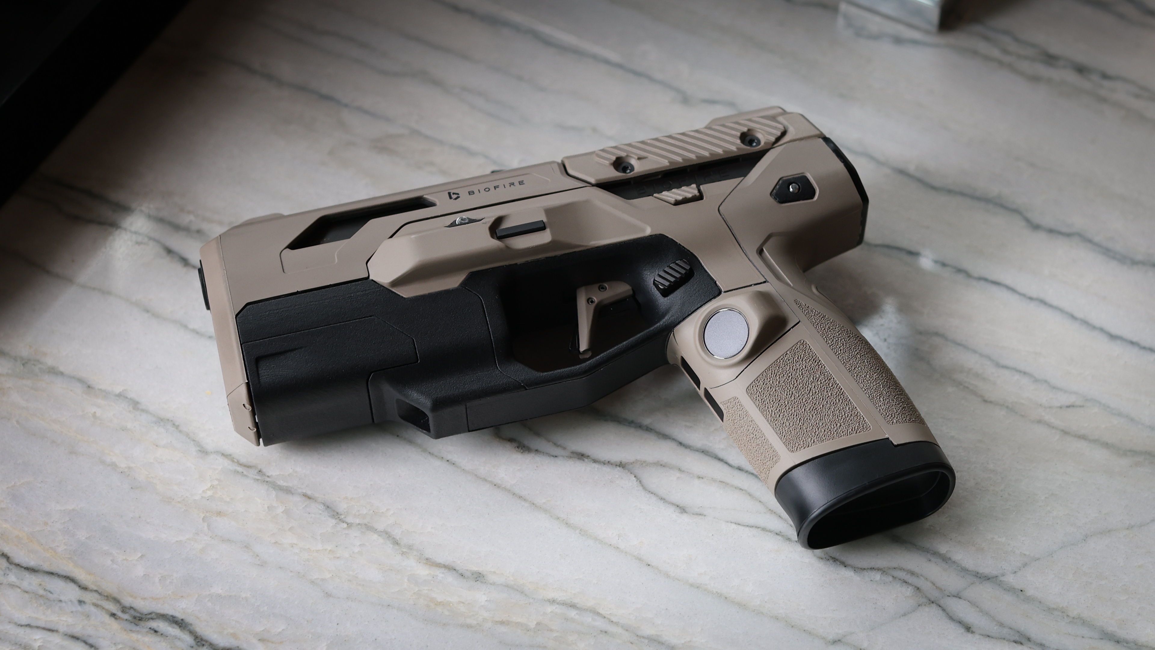 A tan Biofire Smart Gun resting on a light stone countertop.